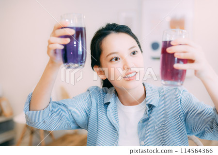 Woman enjoying color change with butterfly pea 114564366