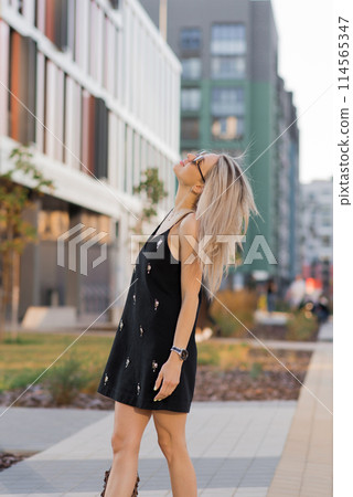 Happy young Caucasian girl in sunglasses walking in the city on a sunny day Happy young Caucasian girl in sunglasses walking in the city on a sunny day 114565347