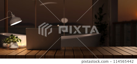 A laptop computer on a tabletop in a modern luxurious bathroom with a bathtub near at night. A laptop computer on a tabletop in a modern luxurious bathroom with a bathtub near at night. 114565442