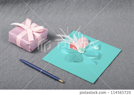 Handmade greeting card. Near gift in wrapping paper, tied with a ribbon. Original gift. Handmade greeting card. Near gift in wrapping paper, tied with a ribbon. Original gift. 114565720