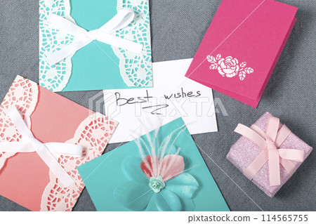 Handmade greeting cards. Near gift in wrapping paper, tied with a ribbon. Original gift. Handmade greeting cards. Near gift in wrapping paper, tied with a ribbon. Original gift. 114565755