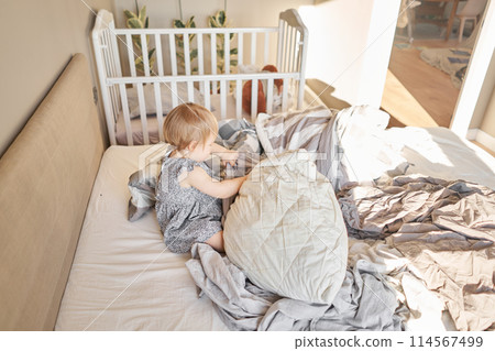 House cleaning. Happy baby girl one and half, helper are having fun and smiling while in a bright apartment. Helps parents change bed linen and do laundry in the washing machine. House cleaning. Happy baby girl one and half, helper are having fun and smiling while in a bright apartment. Helps parents change bed linen and do laundry in the washing machine. 114567499