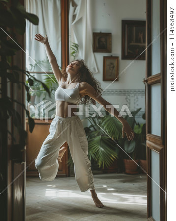 A woman joyfully dances in a room caressed by morning light, her movements a celebration of life and the new day's energy. 114568497