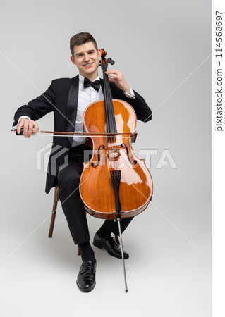 Passionate cello player sitting on chair performing concert 114568697