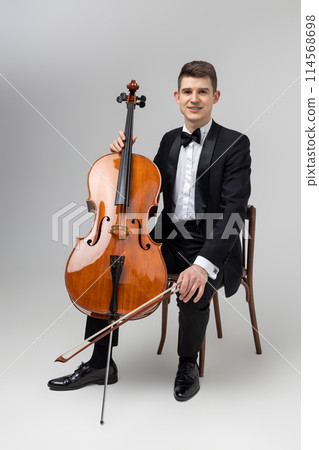 Young male artist sitting on chair and playing contrabass 114568698