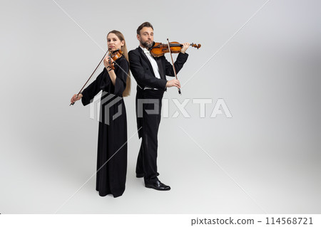 Bearded man and young woman violinist playing classical music at concert Bearded man and young woman violinist playing classical music at concert 114568721