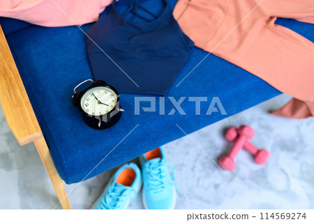 A clock on a sofa with a set of items for a girl doing strength training starting to exercise Preparation Changing clothes Mail order Background material 114569274