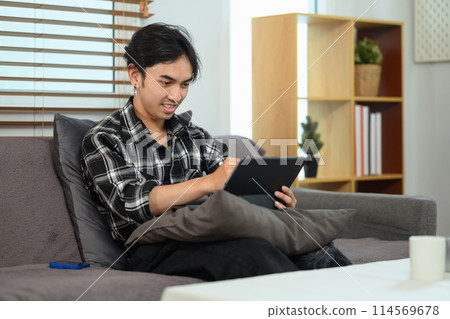 Handsome asian man shopping online, browsing Internet on digital tablet at home 114569678