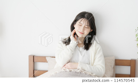 Woman listening to music in bed 114570545