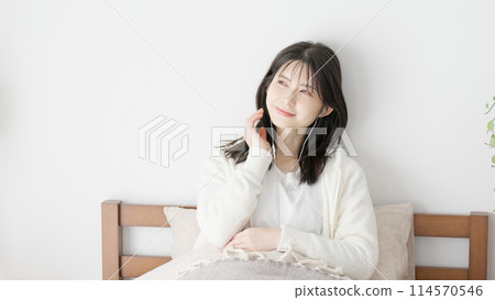 Woman listening to music in bed 114570546