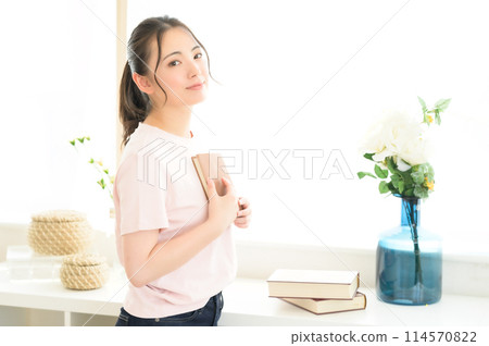 Woman reading a book by the window Woman reading a book by the window 114570822