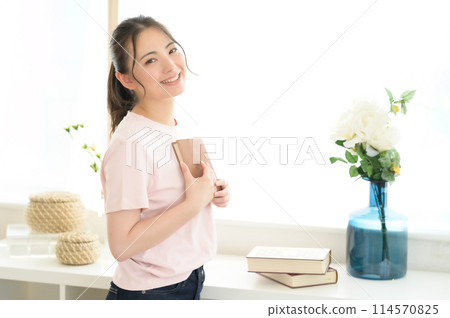 Woman reading a book by the window 114570825