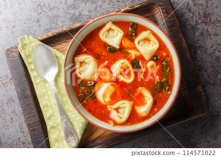 Delicious Creamy Tomato Tortellini Soup with spinach and vegetables closeup on the plate. Horizontal top view Delicious Creamy Tomato Tortellini Soup with spinach and vegetables closeup on the plate. Horizontal top view 114571022