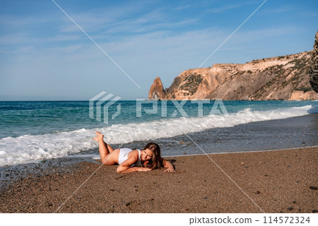 Happy woman in bikini lying on the sea beach. Tanned girl sunbathing on a beautiful shore. Summer vacation or holiday travel concept Happy woman in bikini lying on the sea beach. Tanned girl sunbathing on a beautiful shore. Summer vacation or holiday travel concept 114572324