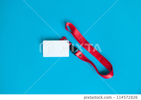 White plastic badge, red Lanyard with blank space mock up isolated on blue background 114572826