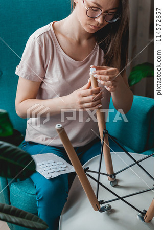 Woman attach felt pad on chair leg, care of floor 114572857