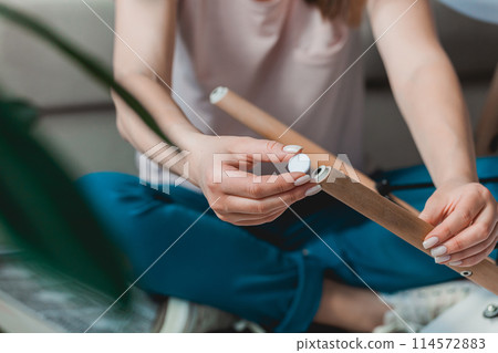 Woman attach felt pad on chair leg, care of floor Woman attach felt pad on chair leg, care of floor 114572883
