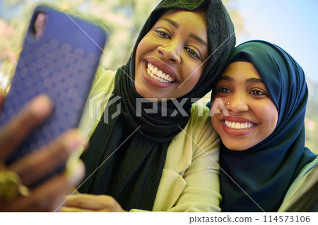 Middle Eastern Muslim Women Capturing Selfies in Serene Surroundings Middle Eastern Muslim Women Capturing Selfies in Serene Surroundings 114573106