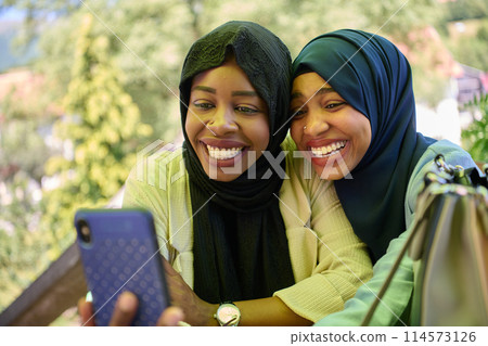Middle Eastern Muslim Women Capturing Selfies in Serene Surroundings Middle Eastern Muslim Women Capturing Selfies in Serene Surroundings 114573126