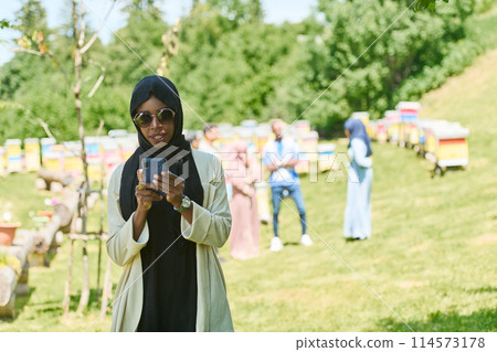 Empowered Middle Eastern Muslim Woman in Hijab Balances Modern Technology and Traditional Beekeeping Business Empowered Middle Eastern Muslim Woman in Hijab Balances Modern Technology and Traditional Beekeeping Business 114573178