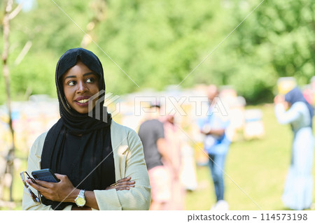 Empowered Middle Eastern Muslim Woman in Hijab Balances Modern Technology and Traditional Beekeeping Business 114573198