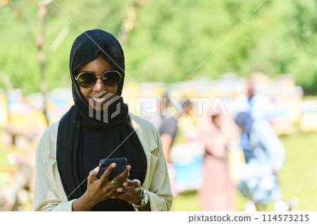 Empowered Middle Eastern Muslim Woman in Hijab Balances Modern Technology and Traditional Beekeeping Business 114573215