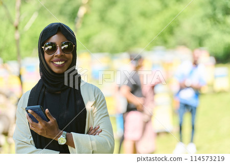 Empowered Middle Eastern Muslim Woman in Hijab Balances Modern Technology and Traditional Beekeeping Business Empowered Middle Eastern Muslim Woman in Hijab Balances Modern Technology and Traditional Beekeeping Business 114573219