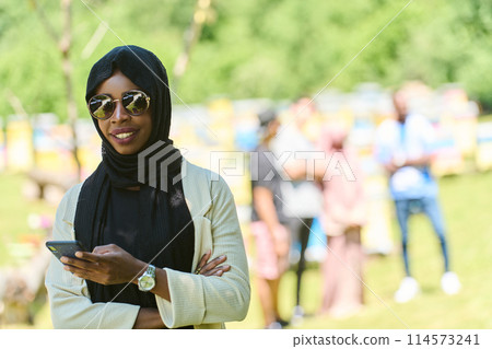 Empowered Middle Eastern Muslim Woman in Hijab Balances Modern Technology and Traditional Beekeeping Business 114573241
