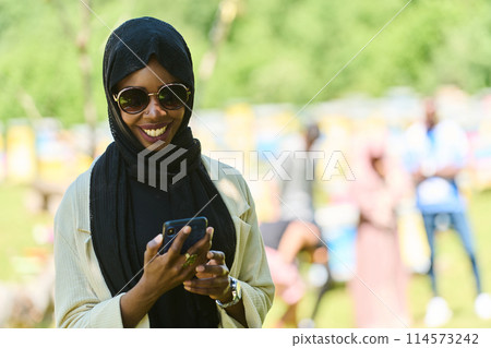 Empowered Middle Eastern Muslim Woman in Hijab Balances Modern Technology and Traditional Beekeeping Business 114573242