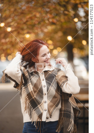 A sunny red-haired woman giggles with glee, infusing the autumn city with joy. A sunny red-haired woman giggles with glee, infusing the autumn city with joy. 114577023