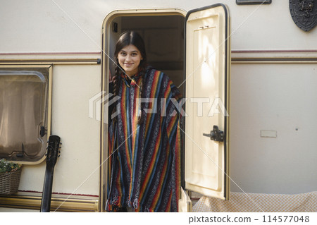 An enchanting lady exudes bohemian vibes against the park scenery, with a trailer in the background. 114577048