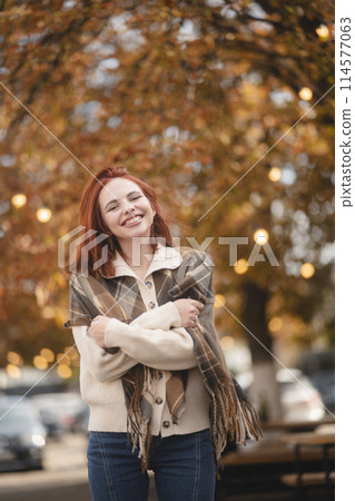 A jubilant redhead beams with laughter, lighting up the autumn city streets. A jubilant redhead beams with laughter, lighting up the autumn city streets. 114577063