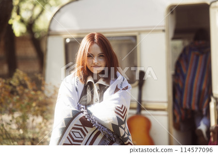 A captivating girl showcases her hippie-inspired look against the park landscape, with a trailer nearby. A captivating girl showcases her hippie-inspired look against the park landscape, with a trailer nearby. 114577096
