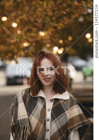 An alluring red-haired woman captivating with her bohemian style on an autumn day. 114577114
