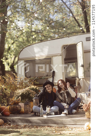A pair of trendy gals don boho-chic attire against the trailer backdrop. A pair of trendy gals don boho-chic attire against the trailer backdrop. 114577195