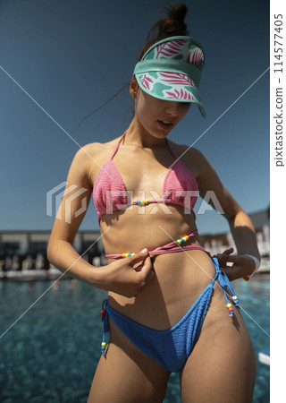 A chic and trendy lady lounges elegantly in her blue bikini by the pool. A chic and trendy lady lounges elegantly in her blue bikini by the pool. 114577405