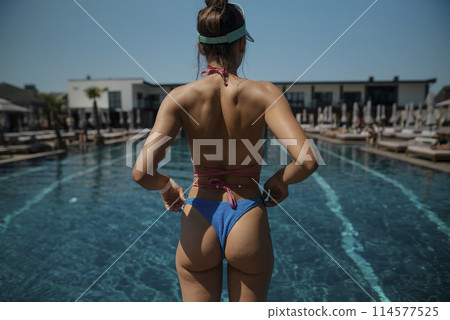 A young woman with a beautiful figure poses in a bikini by the pool. A young woman with a beautiful figure poses in a bikini by the pool. 114577525