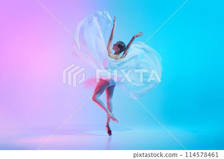 Portrait of young ballerina dancing standing on tiptoe with fabric in neon light against vivid gradient background. Portrait of young ballerina dancing standing on tiptoe with fabric in neon light against vivid gradient background. 114578461