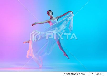Artistic ballerina dancing with white flowing fabric in action in neon light against vivid gradient background. Graceful moment. Artistic ballerina dancing with white flowing fabric in action in neon light against vivid gradient background. Graceful moment. 114578478