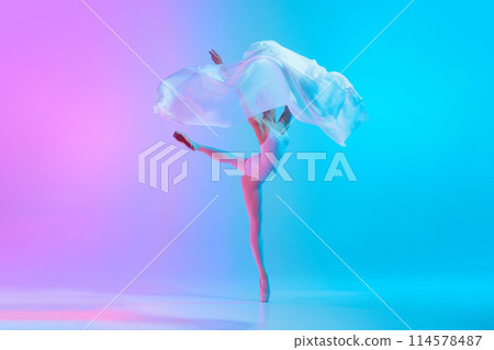 Elegant female dancer performing ballet move with white fabric in motion in neon light against vivid gradient background. Elegant female dancer performing ballet move with white fabric in motion in neon light against vivid gradient background. 114578487