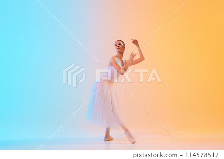 Elegant ballet performer in white tutu and pointe moves in dance in neon light against blue-orange gradient background. 114578512