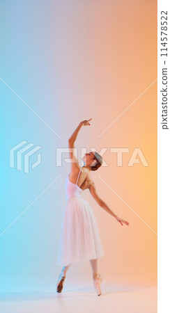 Ballet dancer in white tutu performs an elegant pose in neon light against blue-orange gradient background. Art. 114578522