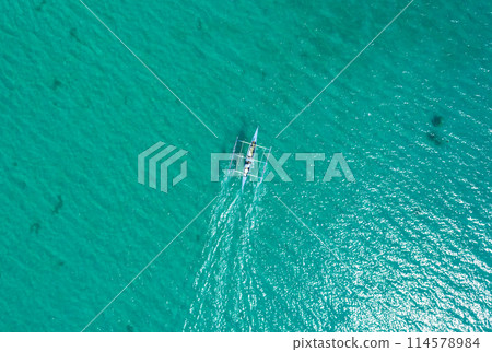 Aerial top view of Banca boat floating in open sea with clear and turquoise water on sunny day . Tropical landscape. Philippines, Palawan. 114578984