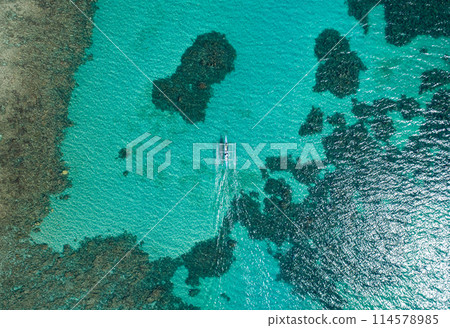 Aerial top view of Banca boat floating in open sea with clear and turquoise water on sunny day . Tropical landscape. Philippines, Palawan. 114578985