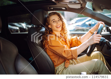 Smiling woman driving a car. Young traveler driving. Car travel, lifestyle concept. 114579631