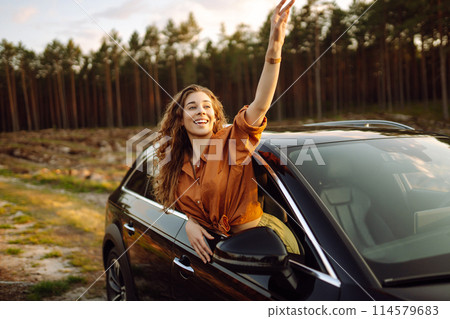 Beautiful traveler woman is resting and enjoying the sunset in the car. Active lifestyle, tourism. Beautiful traveler woman is resting and enjoying the sunset in the car. Active lifestyle, tourism. 114579683