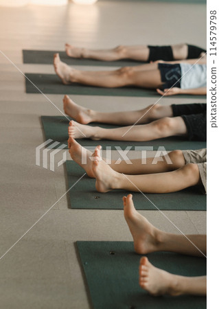 Close-up of the legs of children lying on the floor and doing yoga Close-up of the legs of children lying on the floor and doing yoga 114579798