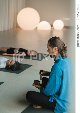 Children relax lying down to the sounds of a Tibetan bowl in the fitness room. Children's yoga Children relax lying down to the sounds of a Tibetan bowl in the fitness room. Children's yoga 114579800