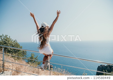 Woman summer travel sea. Happy tourist enjoy taking picture outdoors for memories. Woman traveler posing over sea bay surrounded by volcanic mountains, sharing travel adventure journey Woman summer travel sea. Happy tourist enjoy taking picture outdoors for memories. Woman traveler posing over sea bay surrounded by volcanic mountains, sharing travel adventure journey 114580449