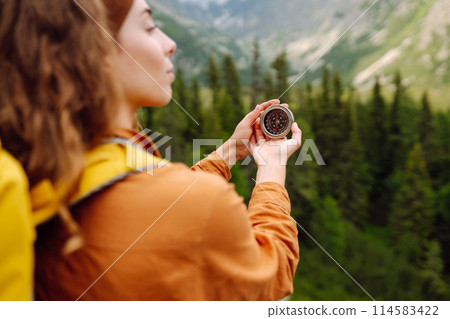 Wanderlust concept. Stylish woman holding a compass in her hand while traveling in the mountains. Wanderlust concept. Stylish woman holding a compass in her hand while traveling in the mountains. 114583422